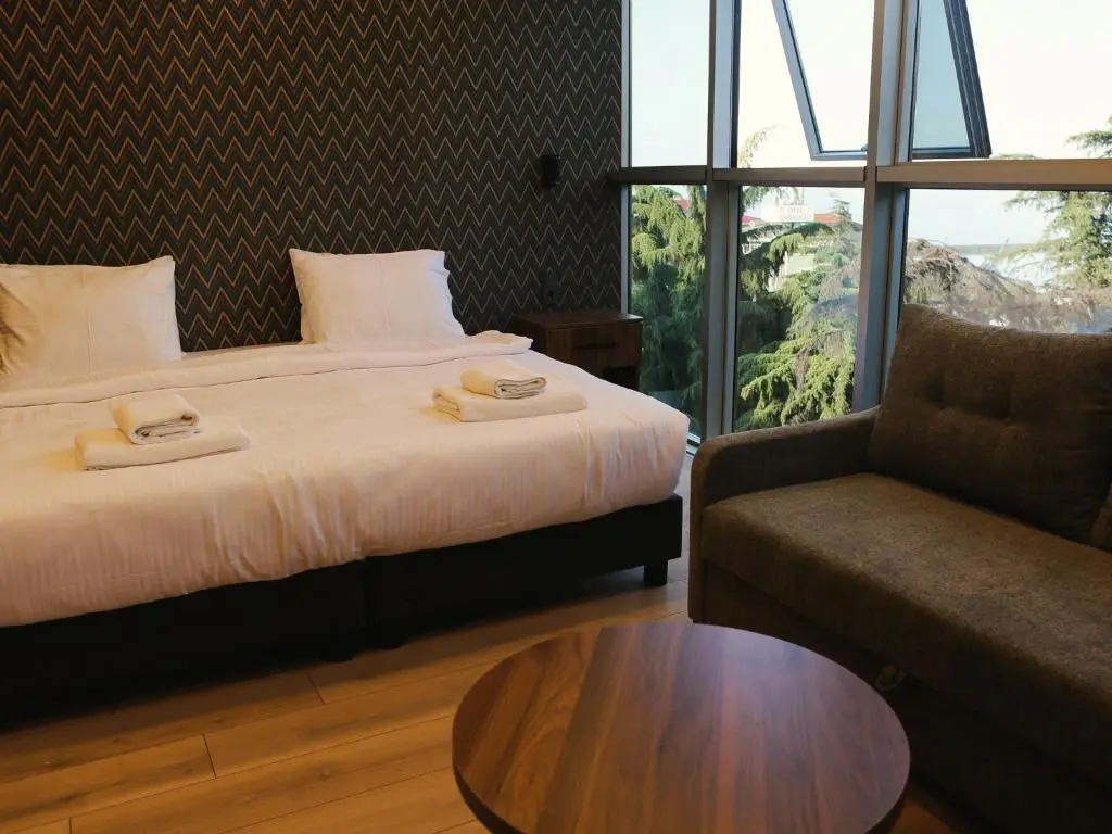 Double Room: bed and zigzag wallpaper; trees and sky behind the glass wall